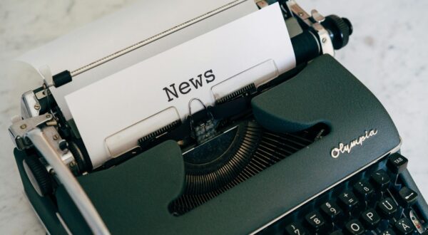 Close-up of an antique typewriter with 'News' on paper.